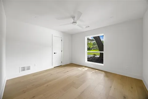 an empty room with windows and fan
