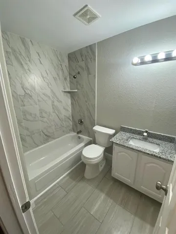 a bathroom with a granite countertop toilet a sink and bathtub