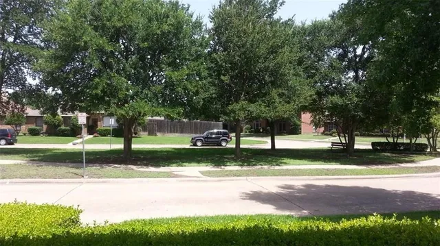 a view of a house with a big yard plants and large trees