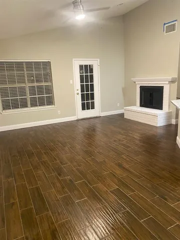 a view of an empty room with wooden floor and windows