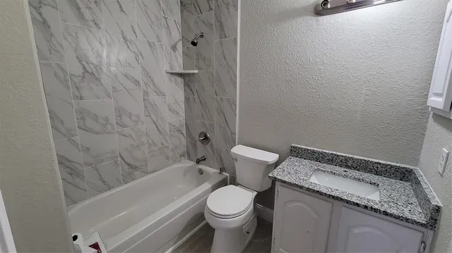a bathroom with a granite countertop toilet and a sink