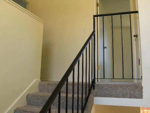 a view of staircase with railing and white walls