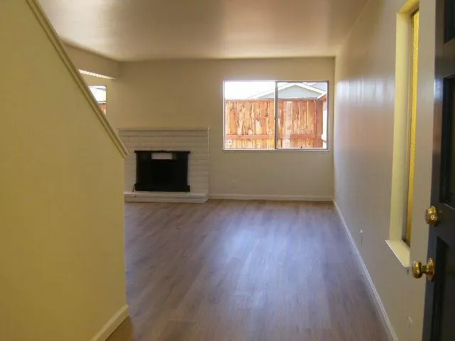an empty room with wooden floor fireplace and windows