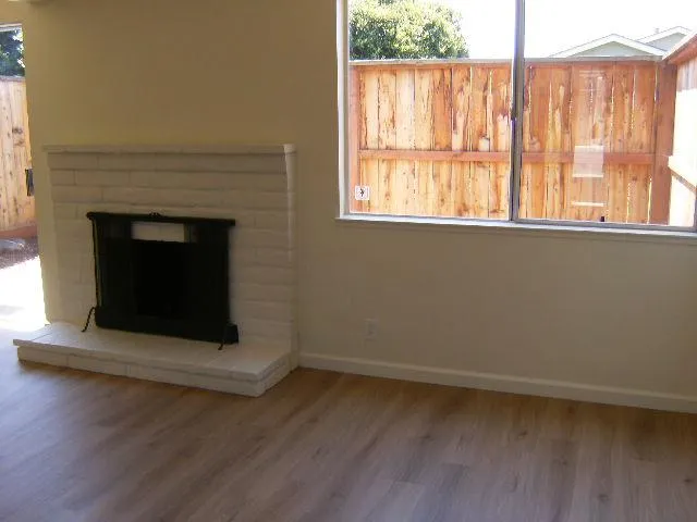 an empty room with wooden floor fireplace and windows