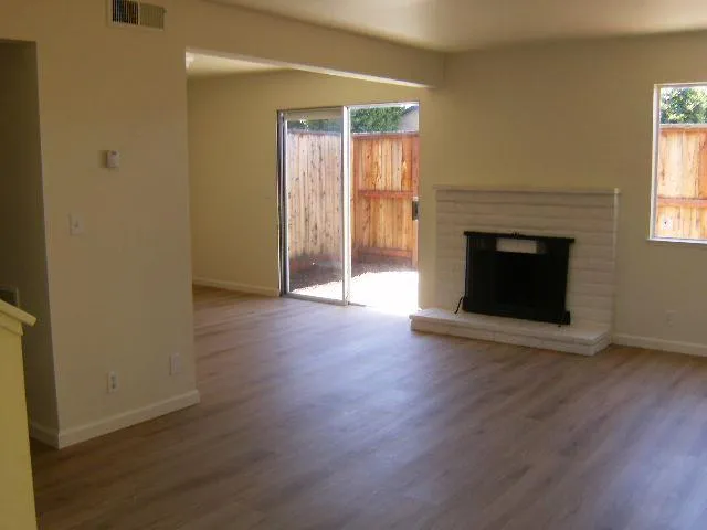 an empty room with wooden floor fireplace and windows