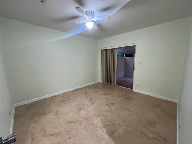 an empty room with a chandelier fan and windows