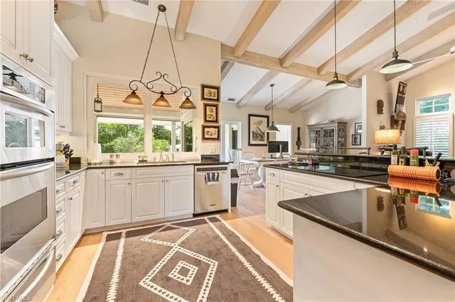 a kitchen with stainless steel appliances granite countertop a sink and white cabinets with wooden floor