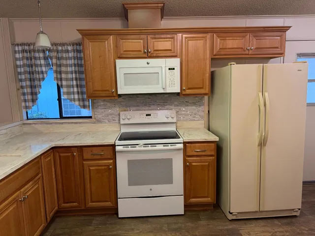 a kitchen with stainless steel appliances a refrigerator a sink a stove top oven a wooden floor and cabinets