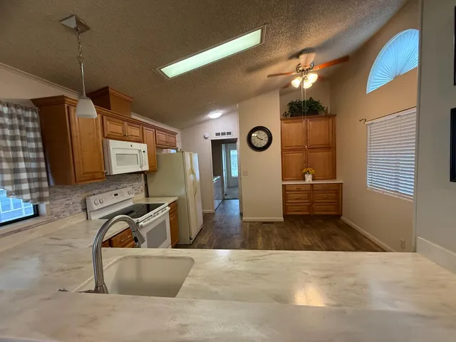 a large white kitchen with stainless steel appliances a refrigerator and a stove top oven