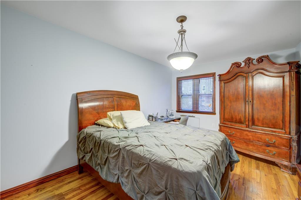 1262 East 73rd Street Brooklyn, NY 11234 - Photo 18 of 26 a bedroom with a bed and a chandelier