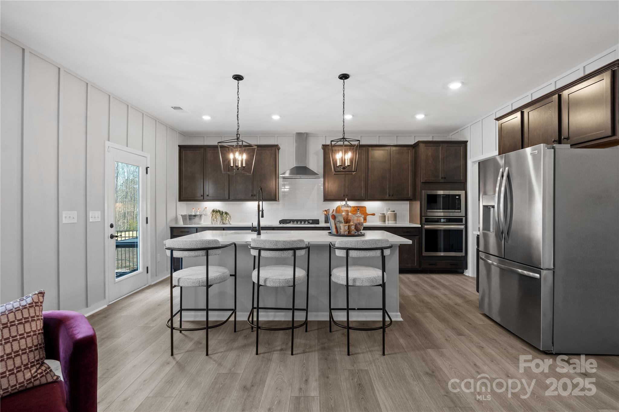 2042 Puddle Pond Road Indian Trail, NC 28079 - Photo 2 of 21 a kitchen with stainless steel appliances granite countertop a refrigerator a sink dishwasher a dining table and chairs with wooden floor