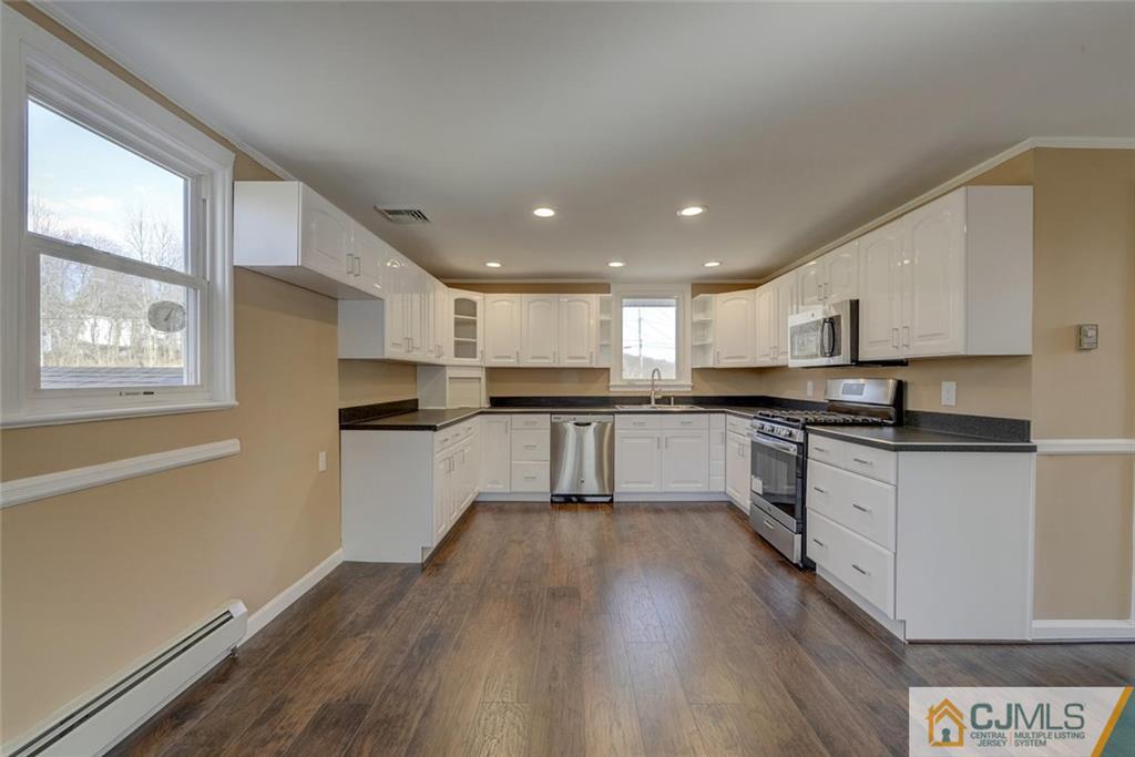 202 Higgins Road Old Bridge, NJ 07747 - Photo 11 of 25 a kitchen with stainless steel appliances granite countertop a stove top oven a sink and white cabinets with wooden floor