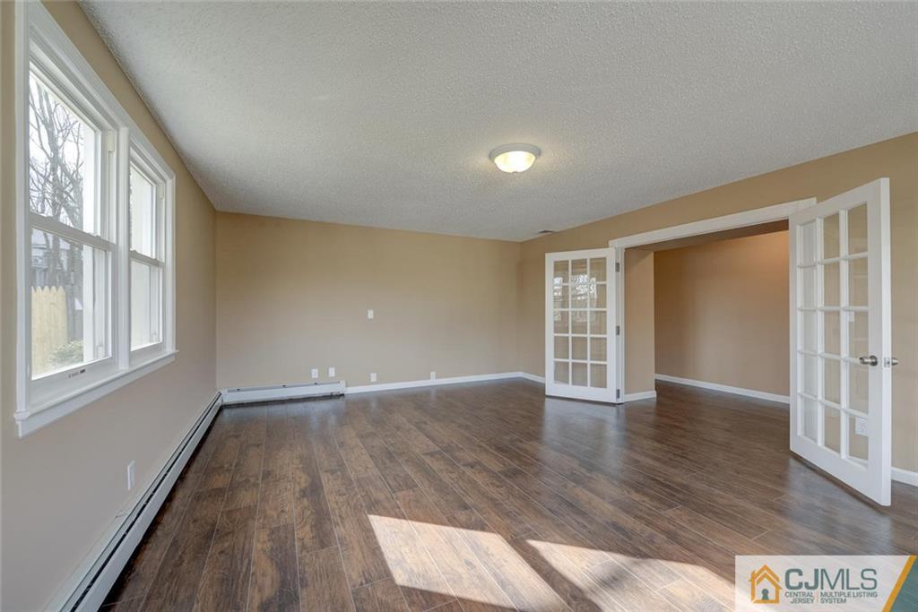 202 Higgins Road Old Bridge, NJ 07747 - Photo 4 of 25 a view of an empty room with wooden floor and a window