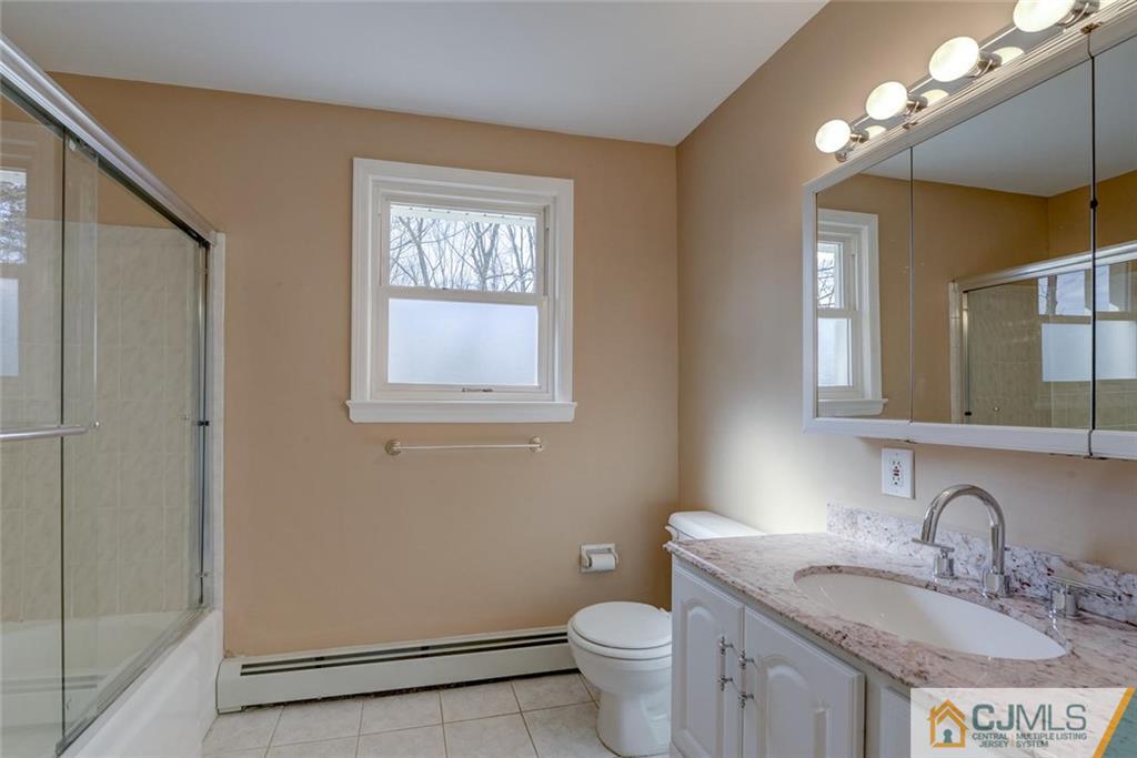 202 Higgins Road Old Bridge, NJ 07747 - Photo 8 of 25 a bathroom with a granite countertop toilet a sink and a mirror