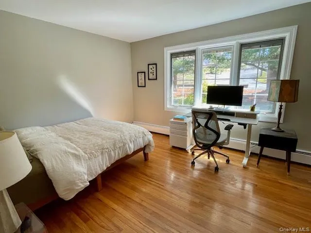 a bedroom with a bed a desk and chair with wooden floor