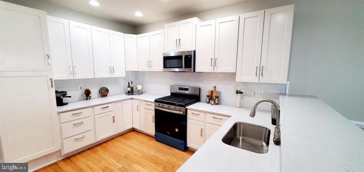 20153 Valhalla Square Ashburn, VA 20147 - Photo 12 of 26 a kitchen with stainless steel appliances granite countertop a stove a sink and white cabinets with wooden floor