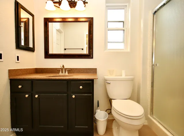 a bathroom with a granite countertop toilet sink and mirror