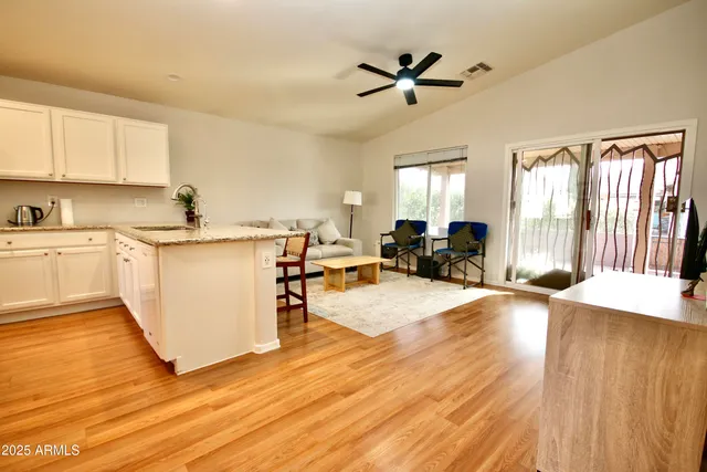 a view of a living room a kitchen island wooden floor and furniture
