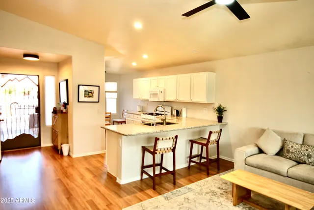 a living room with stainless steel appliances kitchen island a table chairs and a refrigerator