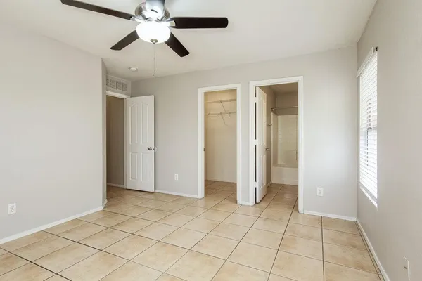 an empty room with closet and a chandelier fan