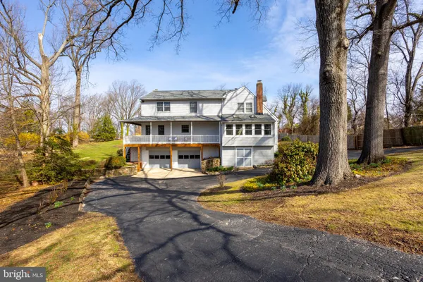 a view of a white house with a big yard and large trees