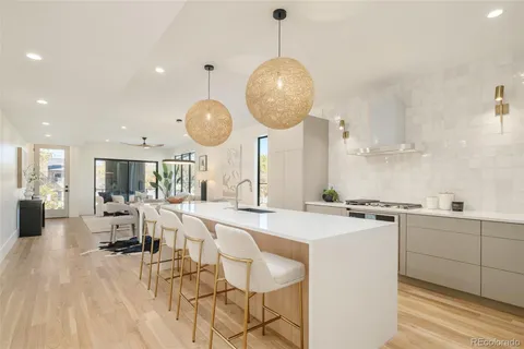 a large kitchen with stainless steel appliances a stove center island a dining table and chairs with wooden floor