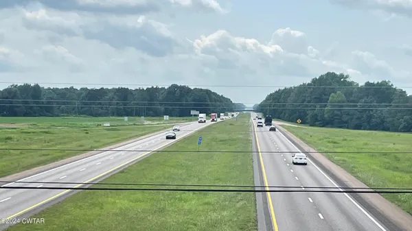 a view of a street with a yard and a house