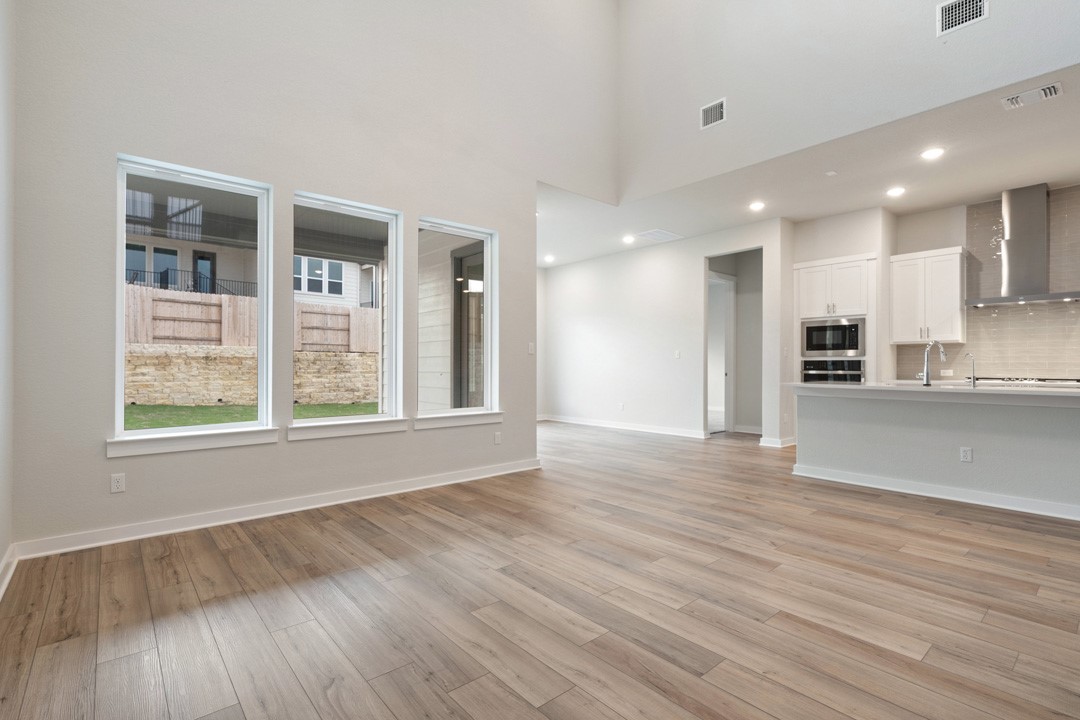 101 Old Wds Road Liberty Hill, TX 78642 - Photo 16 of 40 a view of an empty room with wooden floor and a kitchen