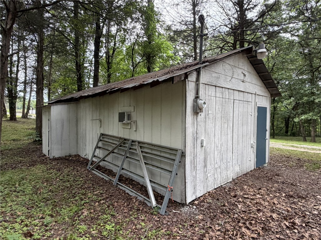 5108 Ridge Road Alma, AR 72921 - Photo 33 of 33 Detached utility building featuring vertical wood siding, a blue-painted access door, and a wall-mounted light fixture
