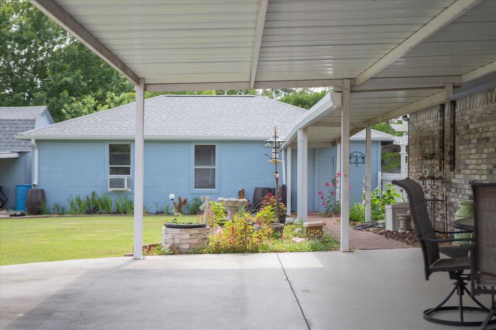107 Fort Graham Circle Waco, TX 76705 - Photo 29 of 39 Covered patio with concrete flooring, supported by white posts, extending towards a brick exterior wall