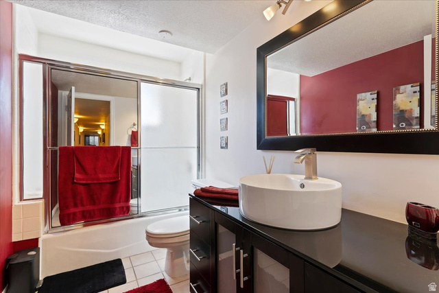 1924 North 2000th Street East Layton, UT 84040 - Photo 33 of 41 Bathroom featuring vanity, a textured ceiling, bath / shower combo with glass door, and light tile patterned floors