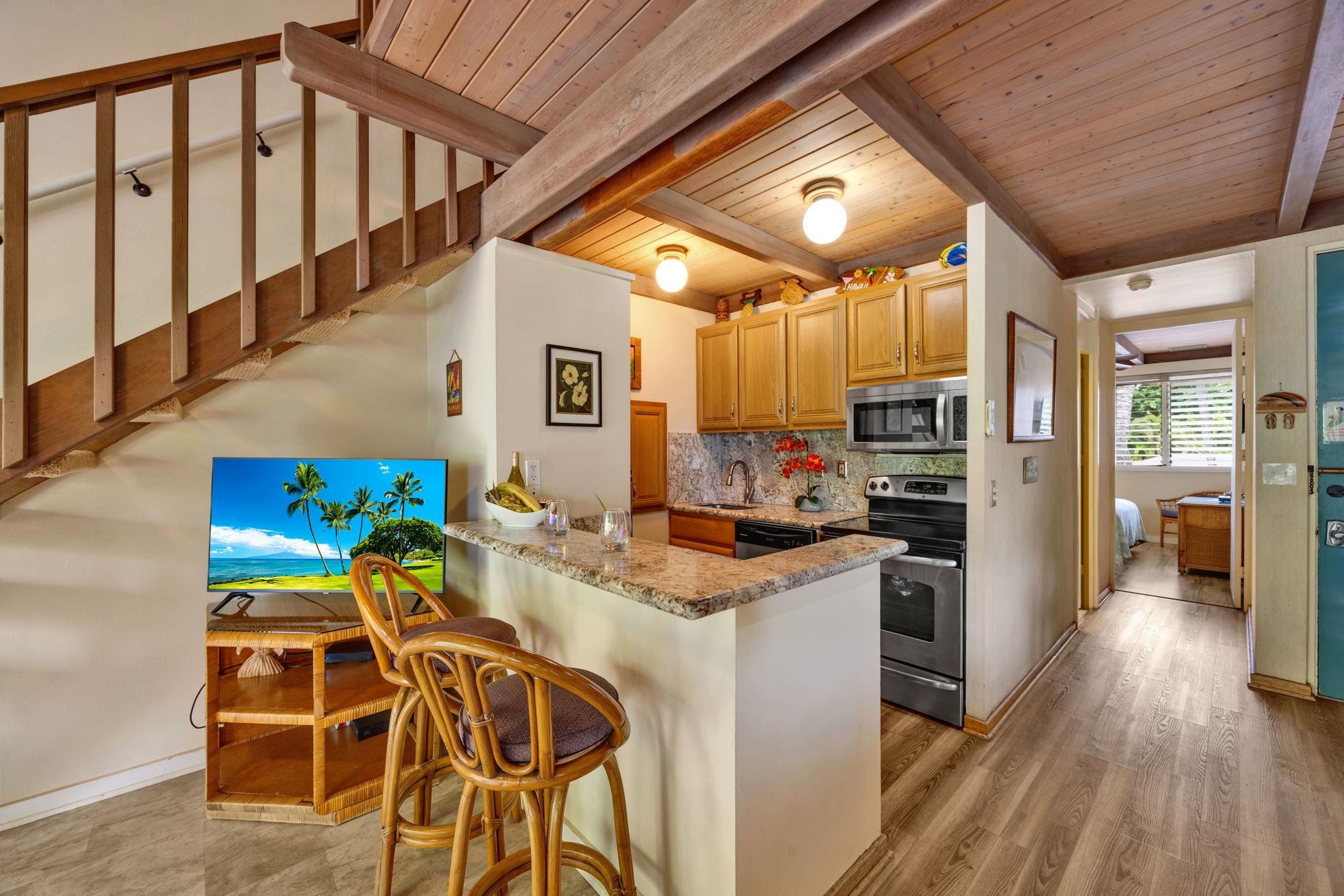 3691 Lower Honoapiilani Road, Unit 211 Lahaina, HI 96761 - Photo 38 of 47 a kitchen with stainless steel appliances kitchen island granite countertop a table chairs and a refrigerator