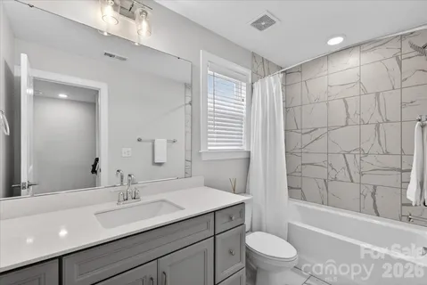 a bathroom with a granite countertop sink a toilet a mirror a vanity and shower