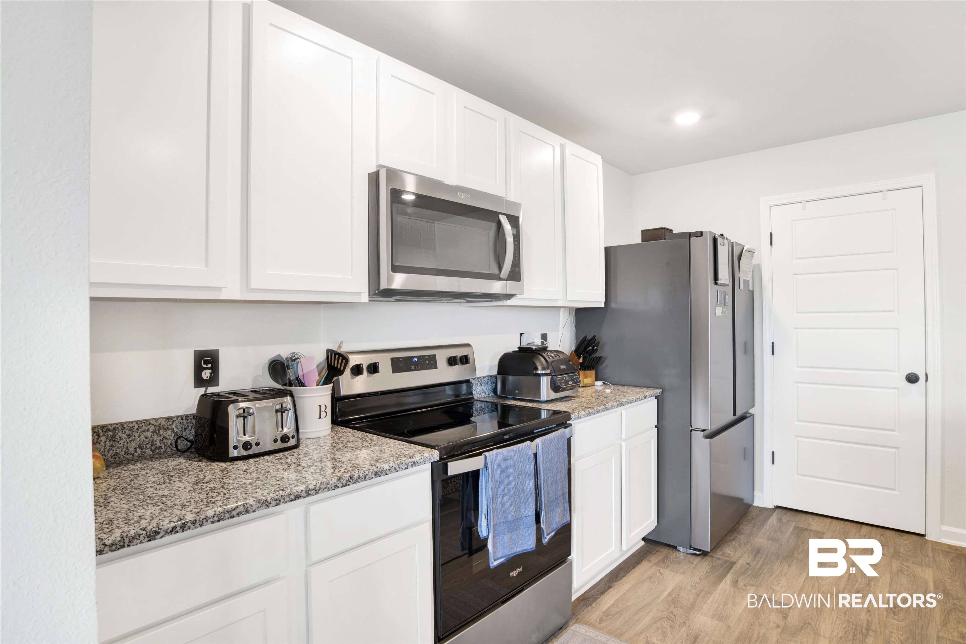 14731 Forsythia Loop Silverhill, AL 36576 - Photo 12 of 25 Kitchen with white cabinets, light stone counters, light hardwood / wood-style flooring, and appliances with stainless steel finishes