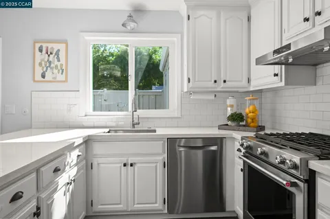 a kitchen with granite countertop a sink stove and cabinets