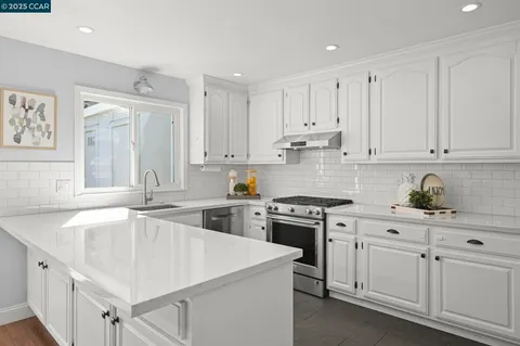 a kitchen with white cabinets sink and stove