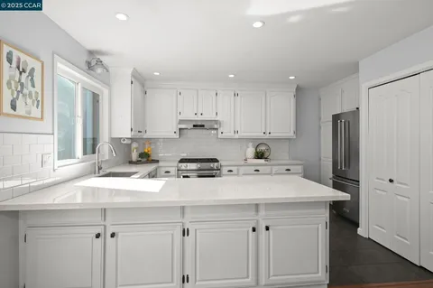 a kitchen with a sink a stove a refrigerator and white cabinets