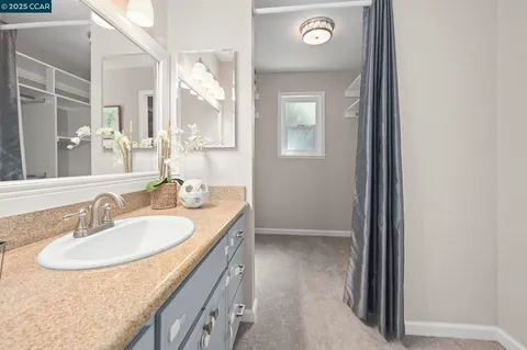 a en suite bathroom with a granite countertop sink and a mirror