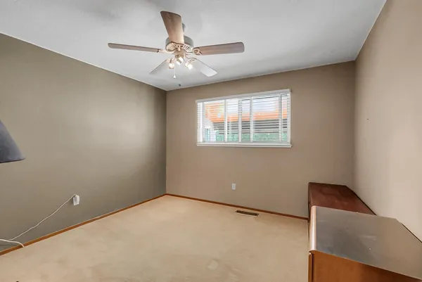an empty room with windows and fan