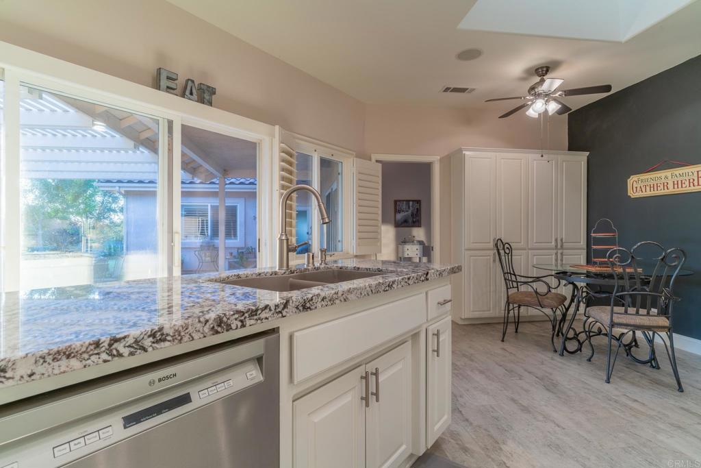 30646 Red Hawk Road Valley Center, CA 92082 - Photo 21 of 69 a kitchen with kitchen island granite countertop a table chairs sink and wooden cabinets