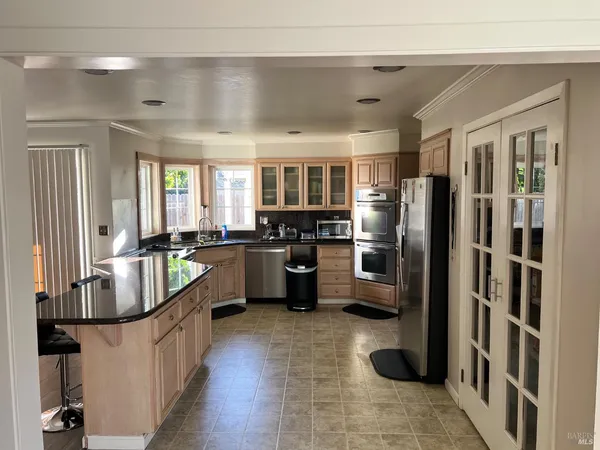 a kitchen with stainless steel appliances a refrigerator a sink a stove top oven a dining table and chairs