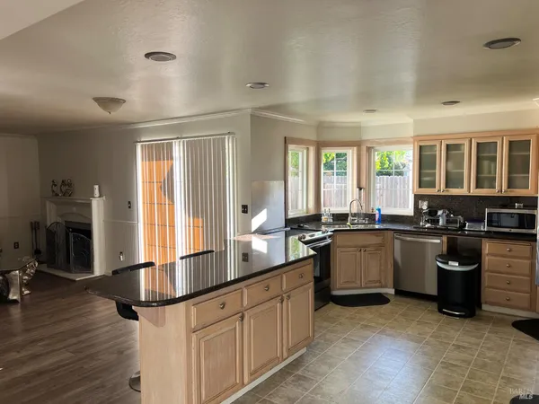 a large kitchen with kitchen island granite countertop a large window and stainless steel appliances