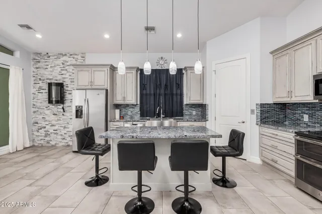 a kitchen with granite countertop a stove a sink a dining table and chairs