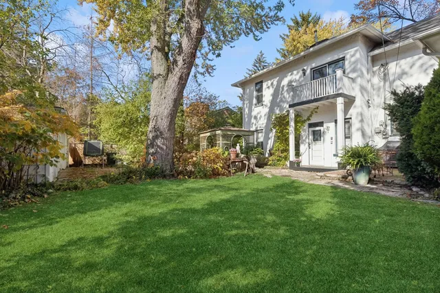 a view of a big house with a big yard and large trees
