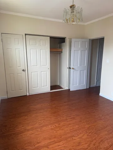 a view of an empty room with wooden floor and cabinet