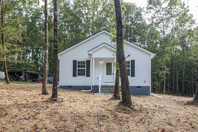 a view of a house with a yard and large tree