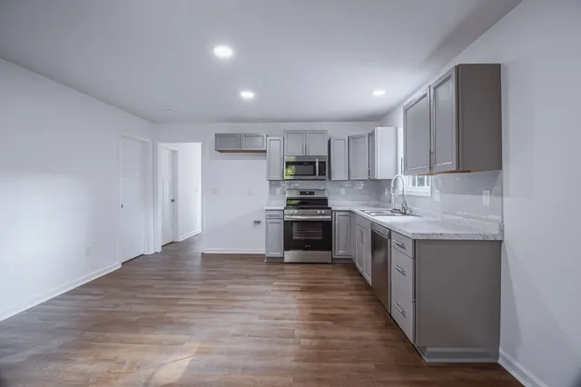 a large kitchen with stainless steel appliances granite countertop a stove a sink and a refrigerator