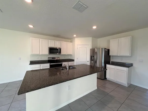 a kitchen with stainless steel appliances granite countertop a sink refrigerator and microwave