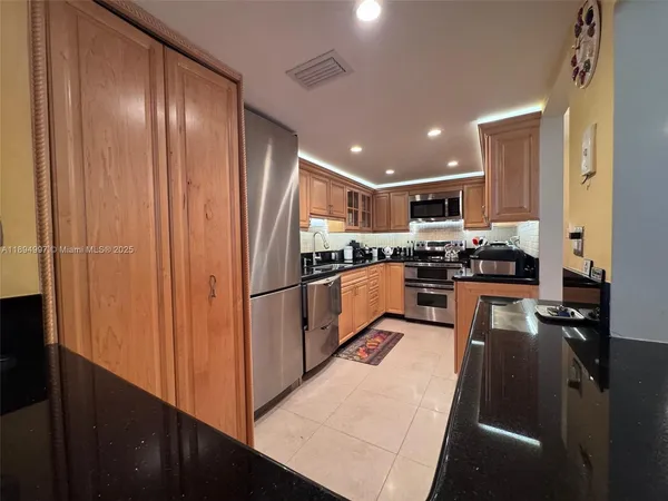 a kitchen with stainless steel appliances granite countertop a refrigerator a stove and a sink with wooden floor