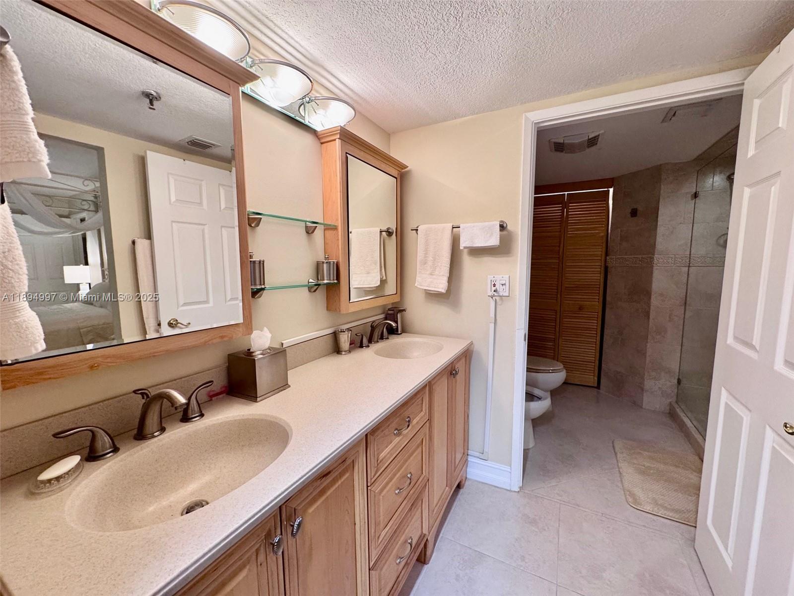 6061 Collins Avenue, Unit 10C Miami Beach, FL 33140 - Photo 6 of 45 a bathroom with a double vanity sink a mirror and a bathtub
